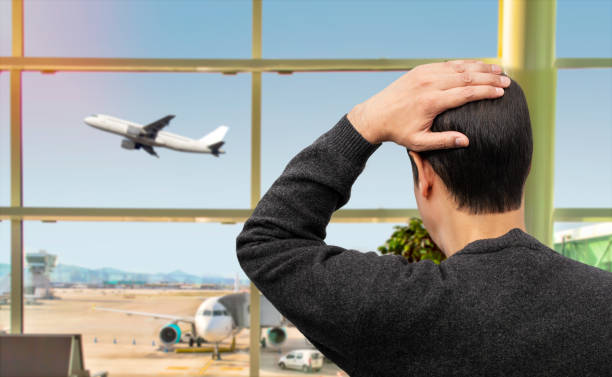 sad man looking his loss flight Rear view of a sad man looking at a plane taking off and missing his flight at airport. How to Handle Travel Delays Like a Pro? stock pictures, royalty-free photos & images